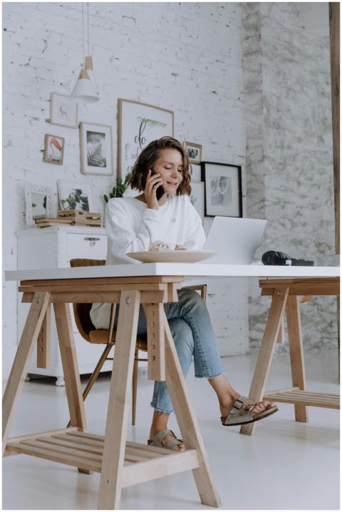 A woman multitasks at home, speaking on the phone