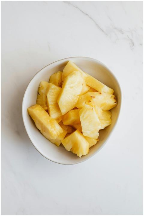 Top view of delicious pineapple pieces in white bo