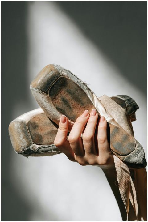 Artistic close-up of worn ballet pointe shoes held