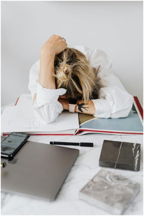 Overwhelmed woman resting head on desk with laptop
