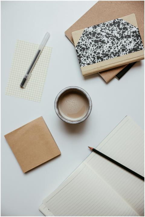 Minimalist flat lay of a coffee cup, notebooks, an