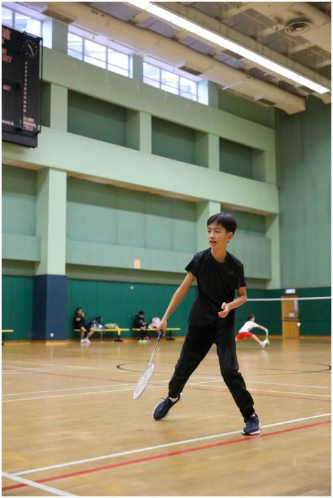 Young boy focused on playing badminton in an indoo