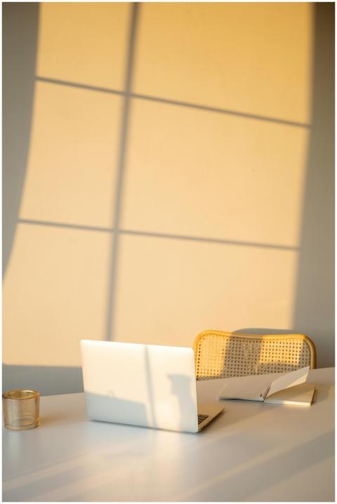 A sunlit office space featuring a laptop and noteb