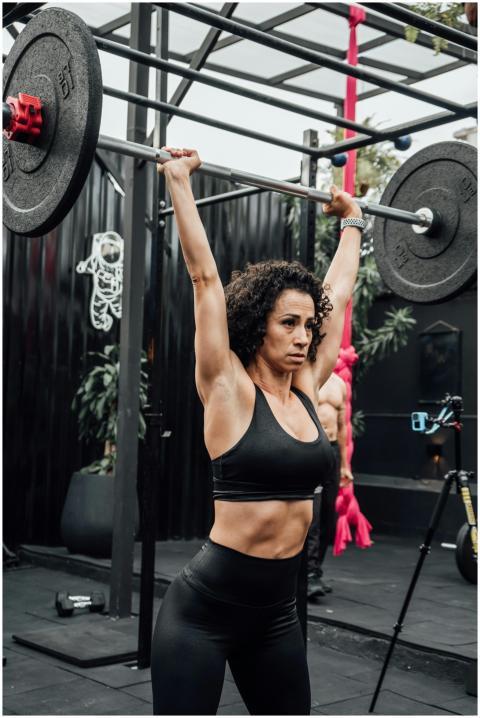Athletic woman lifting weights outside in a gym in