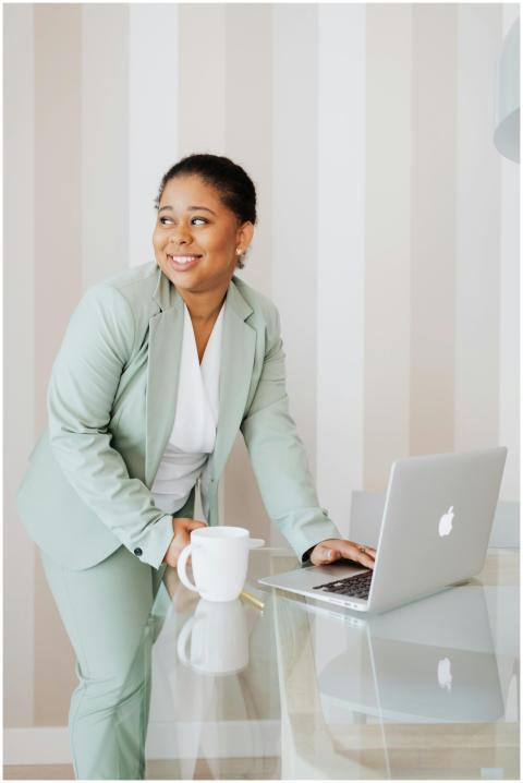 Smiling woman in a mint suit working on a laptop i