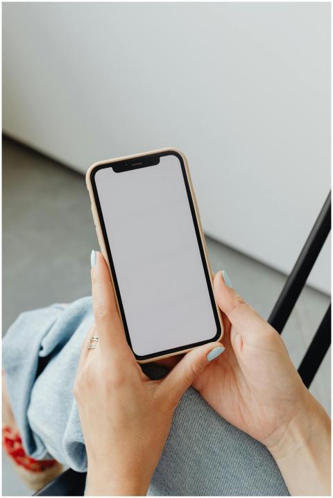 A woman holding a smartphone with a blank screen,