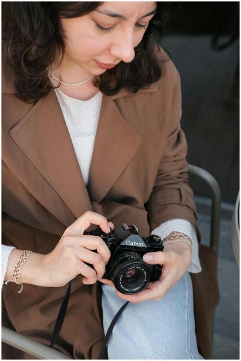 Young woman holding a vintage camera, seated in an