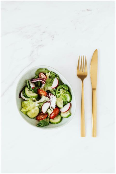 Bowl of fresh vegetable salad with golden cutlery