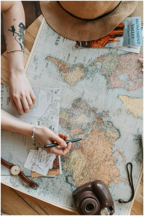 Person planning a journey with a world map, camera