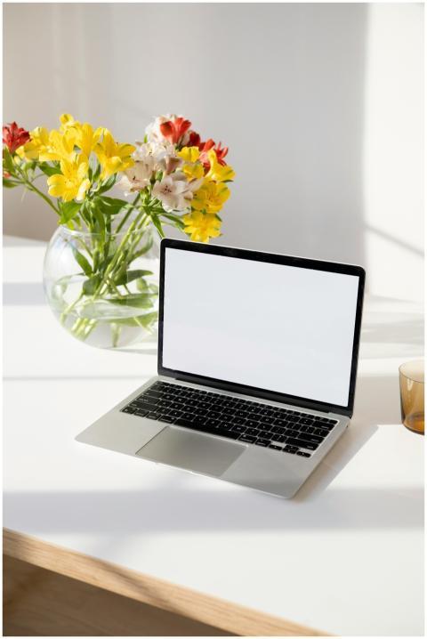 A laptop with a blank screen on a desk, adorned wi