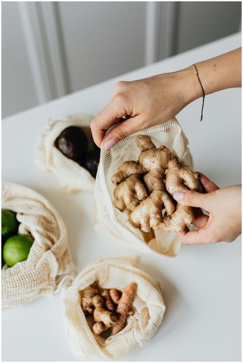 Hands placing ginger into an eco-friendly reusable