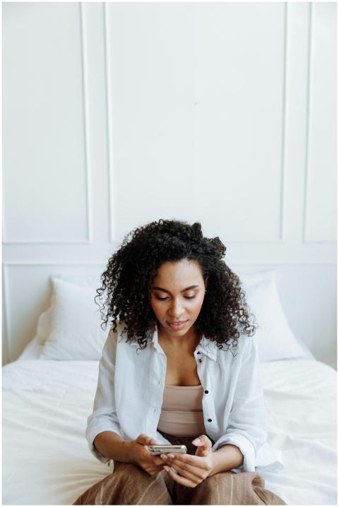 A young woman with curly hair using her smartphone