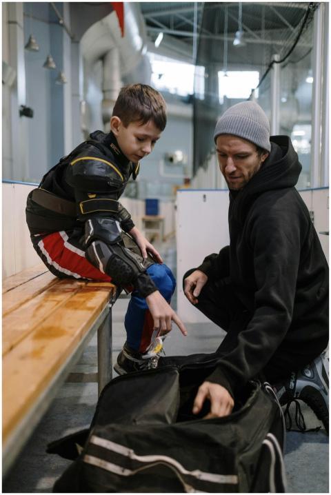A father helping his son prepare for ice hockey pr