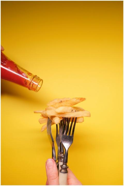 Close-up of fries on forks with ketchup pour again