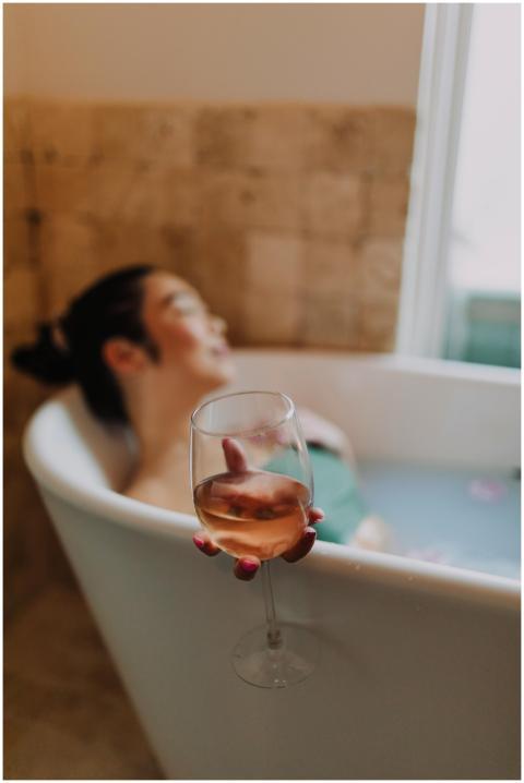 A woman enjoying a relaxing bath holding a glass o