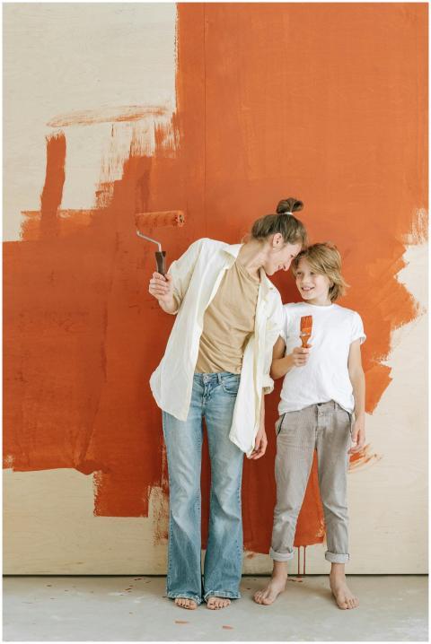 Mother and son smiling while painting a wall toget