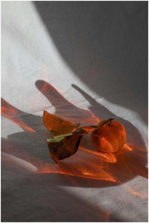 Orange fresh tangerine with green leaf in refracti