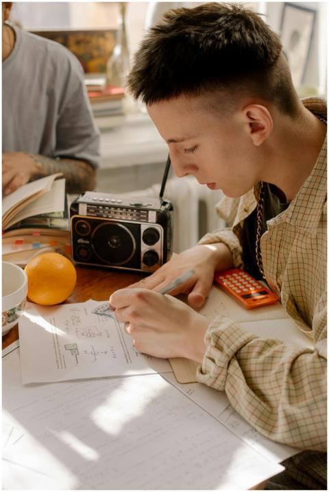 Young student studying with textbooks, calculator,