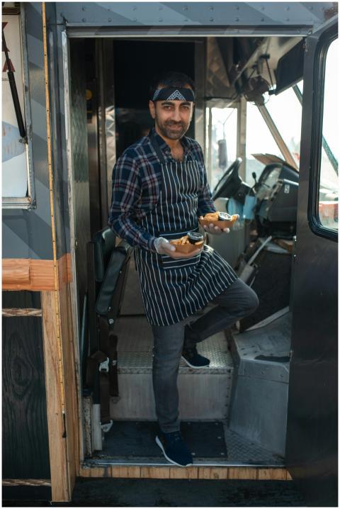 Smiling vendor in a food truck serving delicious s