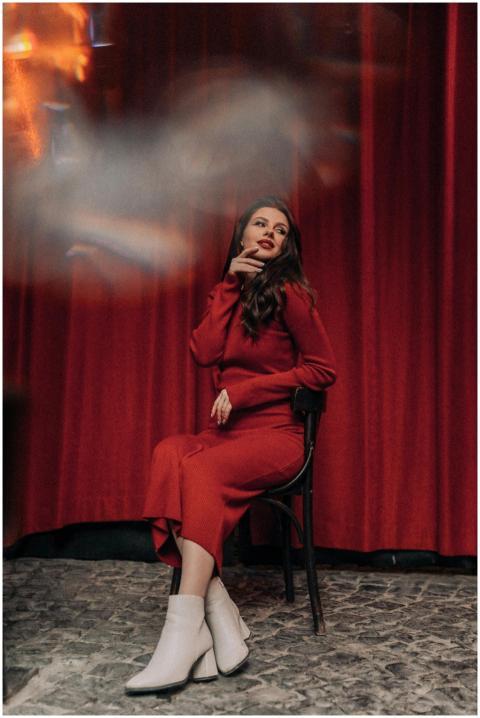 A brunette woman in a red dress sits gracefully in