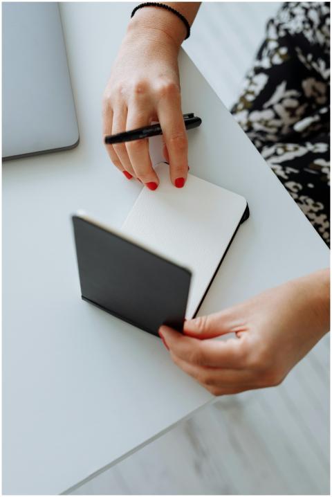 Close-up of hands holding a notepad and pen on a w
