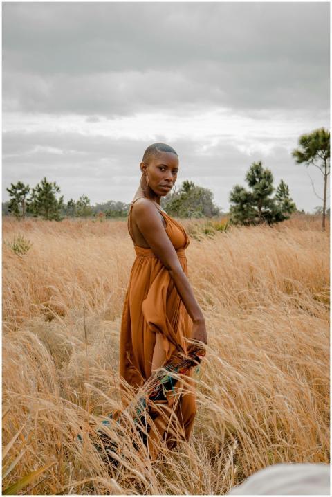 A stylish woman poses elegantly in a golden field