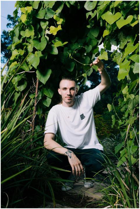 A young man wearing a white t-shirt crouches among