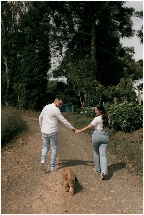 A couple strolls with a dog down a rustic path sur