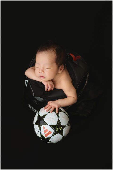 Cute sleeping baby cuddling a soccer ball, creatin
