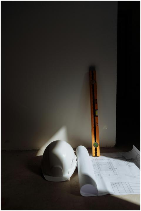 A hard hat, level, and blueprints in a constructio