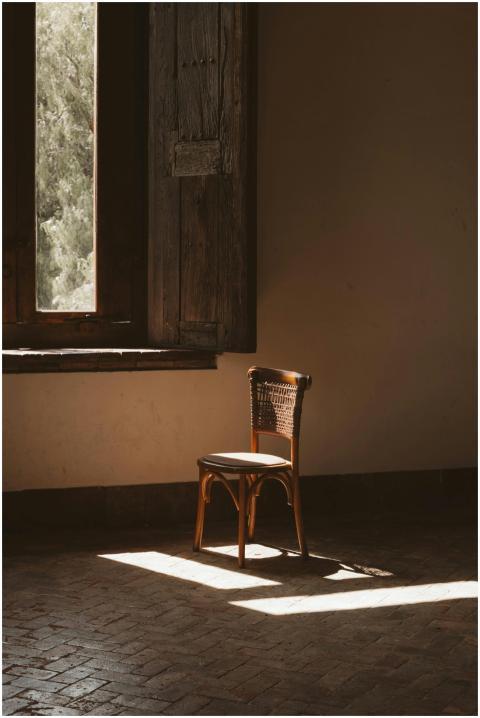 A rustic wooden chair bathed in sunlight by an old