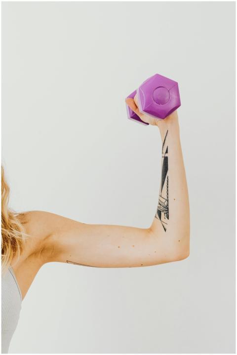 Close-up of a tattooed arm lifting a purple dumbbe