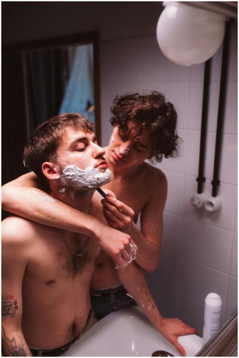 Two young adults share a tender moment shaving in