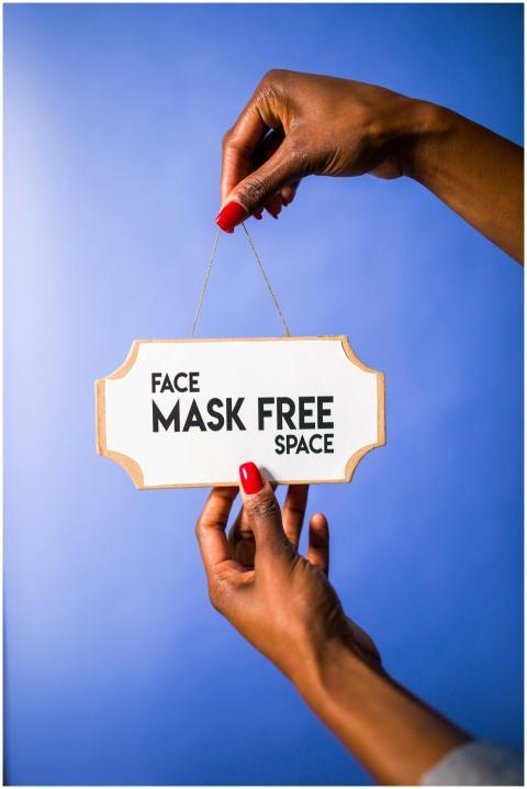 Close-up of hands holding a sign with 'Face Mask F