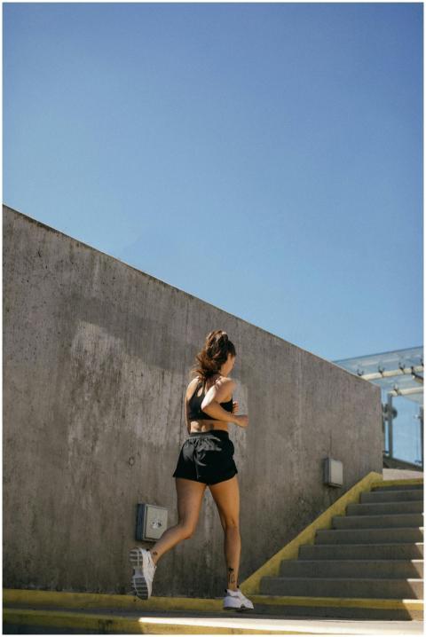 Fit woman running up outdoor stairs in sunny weath