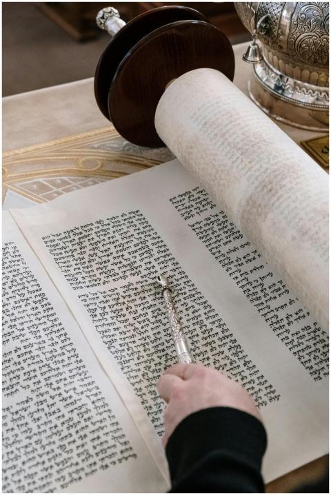 A detailed close-up of a Torah scroll with a yad p