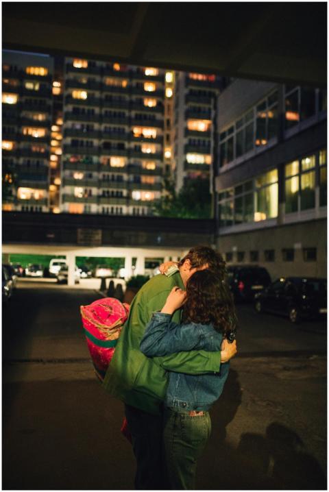A couple embraces under city lights, creating a wa