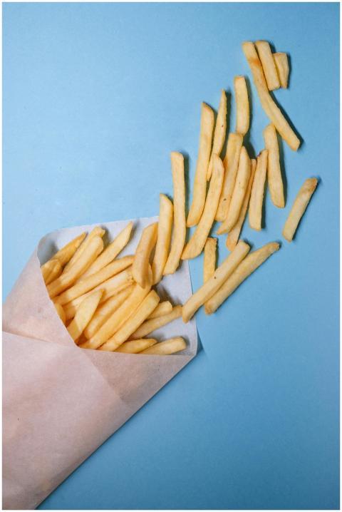 Crispy French fries spilling from paper on a brigh