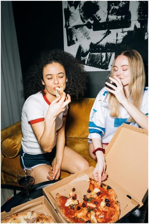 Two young women having fun with pizza and wine, sh