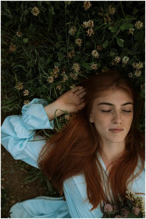 Serene woman with eyes closed lying in a meadow, e