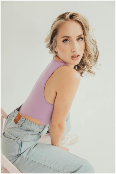 Stylish woman in a lilac top and jeans posing in a