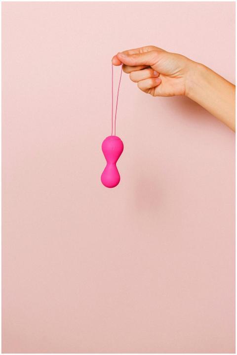 Close-up of a hand holding pink silicone ben wa ba