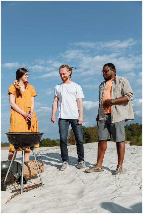 A diverse group enjoying a beach barbecue with a c