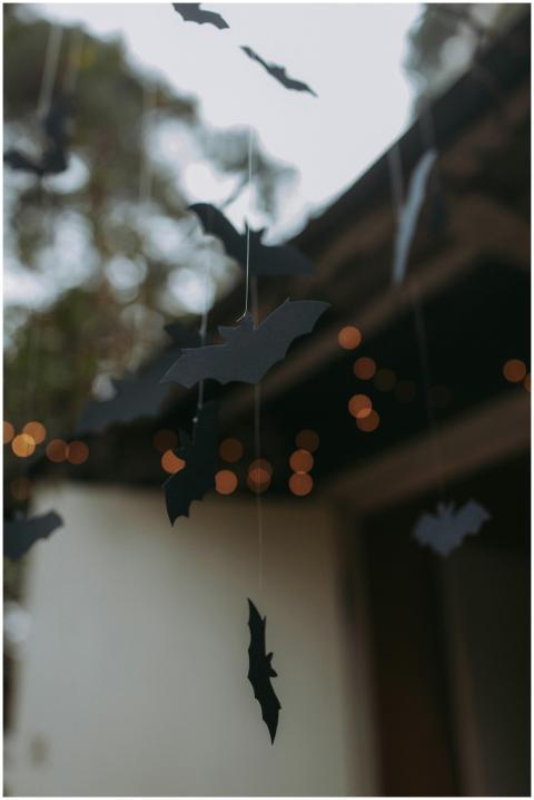Paper bat cutouts hanging outdoors creating a spoo