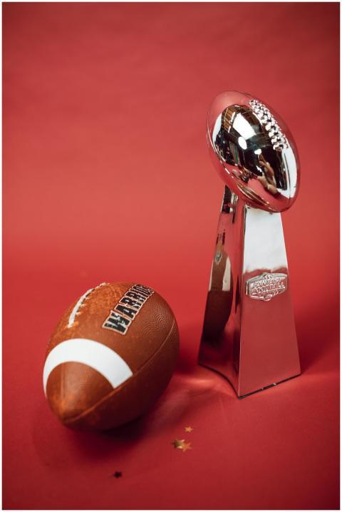 Football and silver trophy on red backdrop symboli