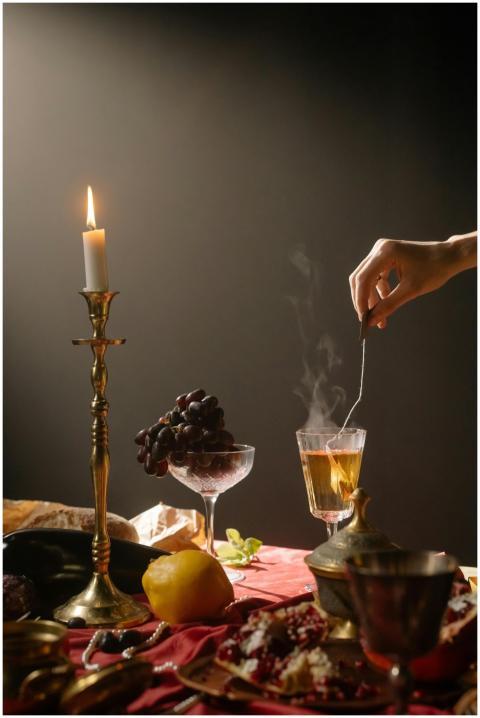 A candlelit still life featuring steaming tea, gra