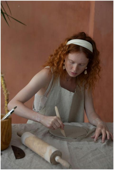 A focused woman shaping a ceramic plate by hand in