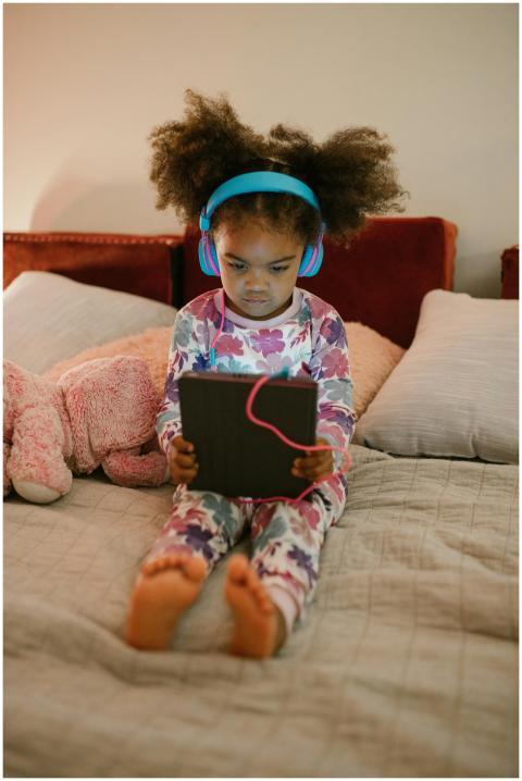 Little girl with headphones and tablet, sitting ba