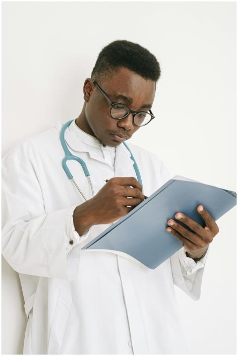 A doctor wearing eyeglasses writes on a medical ch