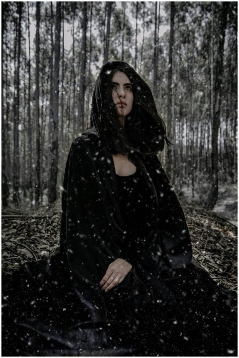 A mysterious woman sits in a snowy winter forest,
